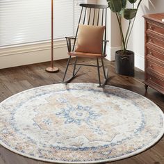 a living room with a rocking chair, rug and plant in the corner on the floor