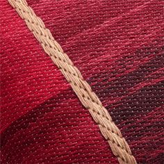 red and brown fabric with some white thread on it's side, close up