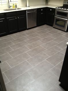 an empty kitchen with black cabinets and stainless steel stove top oven, dishwasher