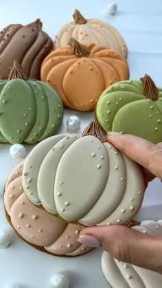 a person holding some cookies in front of them on a white table with pumpkins