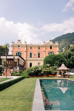 an outdoor pool in front of a large building with a gazebo on the lawn