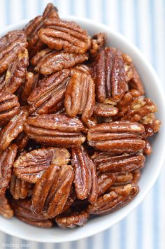 a white bowl filled with pecans on top of a blue and white table cloth