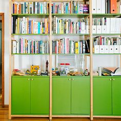 a green bookcase filled with lots of books on top of a hard wood floor