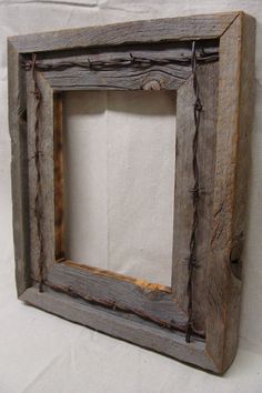 an old wooden frame with barbed wire around the edges on a plain white wall background