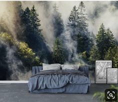 a bed sitting in front of a forest filled with fog and mist wall mural on the side of a bedroom