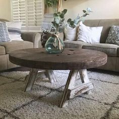 a living room with a couch, coffee table and flowers in vase on top of it