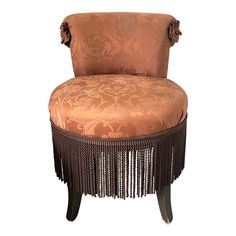 an upholstered chair with tassels on the legs and back, sitting in front of a white background