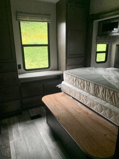 a bed sitting in the middle of a room next to a window with grass outside