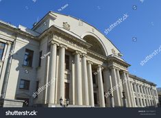 an old building with columns and arches on the front, against a clear blue sky