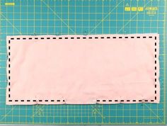 a piece of pink paper with black stitching on top of a green cutting mat