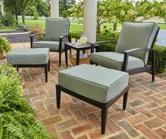 four chairs and a ottoman on a brick patio in front of a house with trees