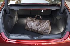 a brown louis vuitton bag sitting in the trunk of a red car