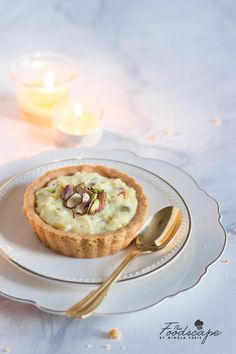 there is a small dessert on the plate with a spoon and two candles in the background