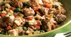 a green bowl filled with meat and rice on top of a table next to a fork