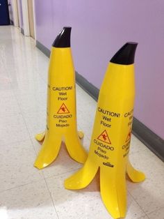 two yellow caution cones sitting next to each other on the floor in front of a purple wall