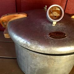 an old metal pot with a gauge on it's lid sitting on a wooden table