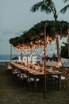 an outdoor dining area with lights strung from the palm trees and love sign on the wall