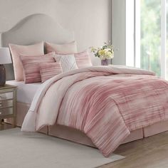 a bed with pink comforters and pillows in a room