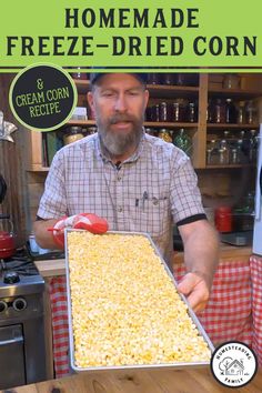 a man holding a tray of corn in front of a stove with the words homemade freeze - dried corn on it