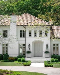 a large white house with lots of windows and bushes in front of the entrance to it