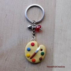 a heart shaped cookie with paintbrushes on it and a key chain attached to it