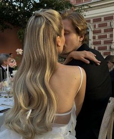 a man and woman kissing each other at a dinner table