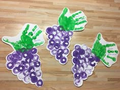 three grape handprints with green and purple grapes on them