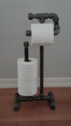 two rolls of toilet paper sitting on top of a black pipe stand next to each other