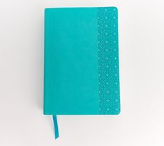 a blue notebook sitting on top of a white table next to a green bookmark