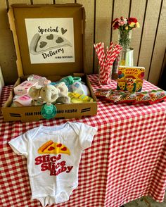 a baby's first birthday gift box with teddy bears and other items on a checkered table cloth