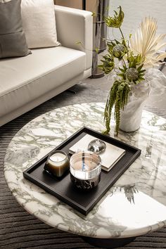 a marble coffee table with two bowls on it and a vase filled with flowers in the middle