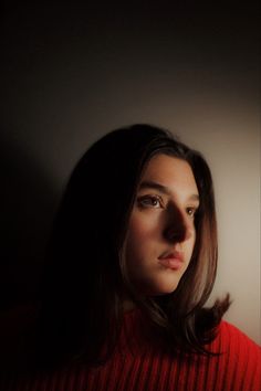 a woman in a red sweater looking off into the distance