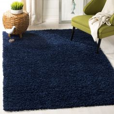 a blue rug in a living room with a chair and potted plant on the floor