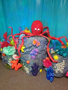 an octopus is sitting on top of a rock surrounded by other sea creatures and corals