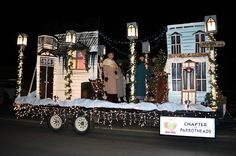 people are standing on the back of a truck decorated with christmas lights and decorations at night