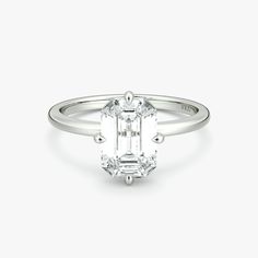 an emerald cut diamond engagement ring with three clawed shans on the band and side stones