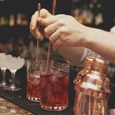 bartenders are making drinks at the bar with copper shakers and glasses on the counter