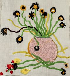 a pink vase with yellow and black flowers in it on a white cloth covered surface