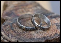 two wedding rings sitting on top of a piece of wood