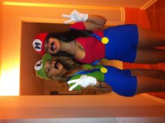 two women dressed up as mario and luigi in the hallway with their hands painted like peace signs