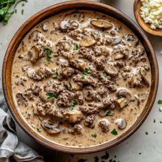 a wooden bowl filled with mushroom soup next to rice and parsley on the side