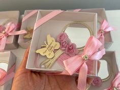 a hand holding a box with pink ribbon and flowers on it, surrounded by other boxes