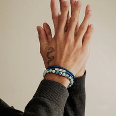 a person wearing a bracelet with a snake on it's wrist and holding their hand up to the camera