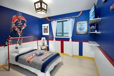 a bedroom decorated in blue, red and white with a hockey theme on the wall