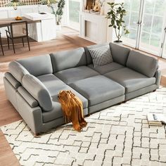 a large gray couch sitting on top of a wooden floor next to a white rug