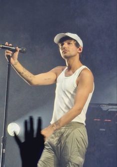 a male in a white tank top and khaki pants is holding a microphone