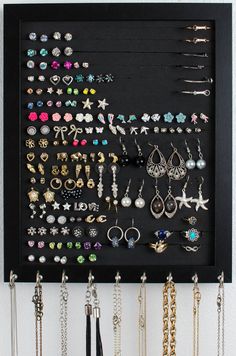 a white frame holding several pairs of earrings and necklaces on it's side