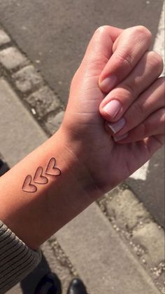 a woman's arm with a small heart tattoo on the middle of her wrist