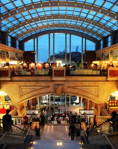 people are walking up and down an escalator in a shopping mall at dusk