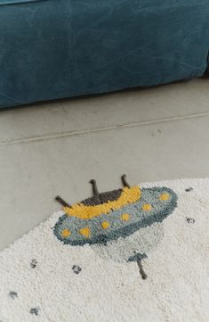 a blue couch sitting next to a rug on top of a white floor covered in yellow and black stars